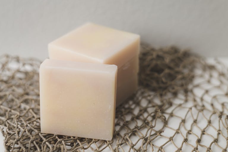 Two bars of natural handmade soap placed on a rustic netting backdrop, perfect for a spa theme.