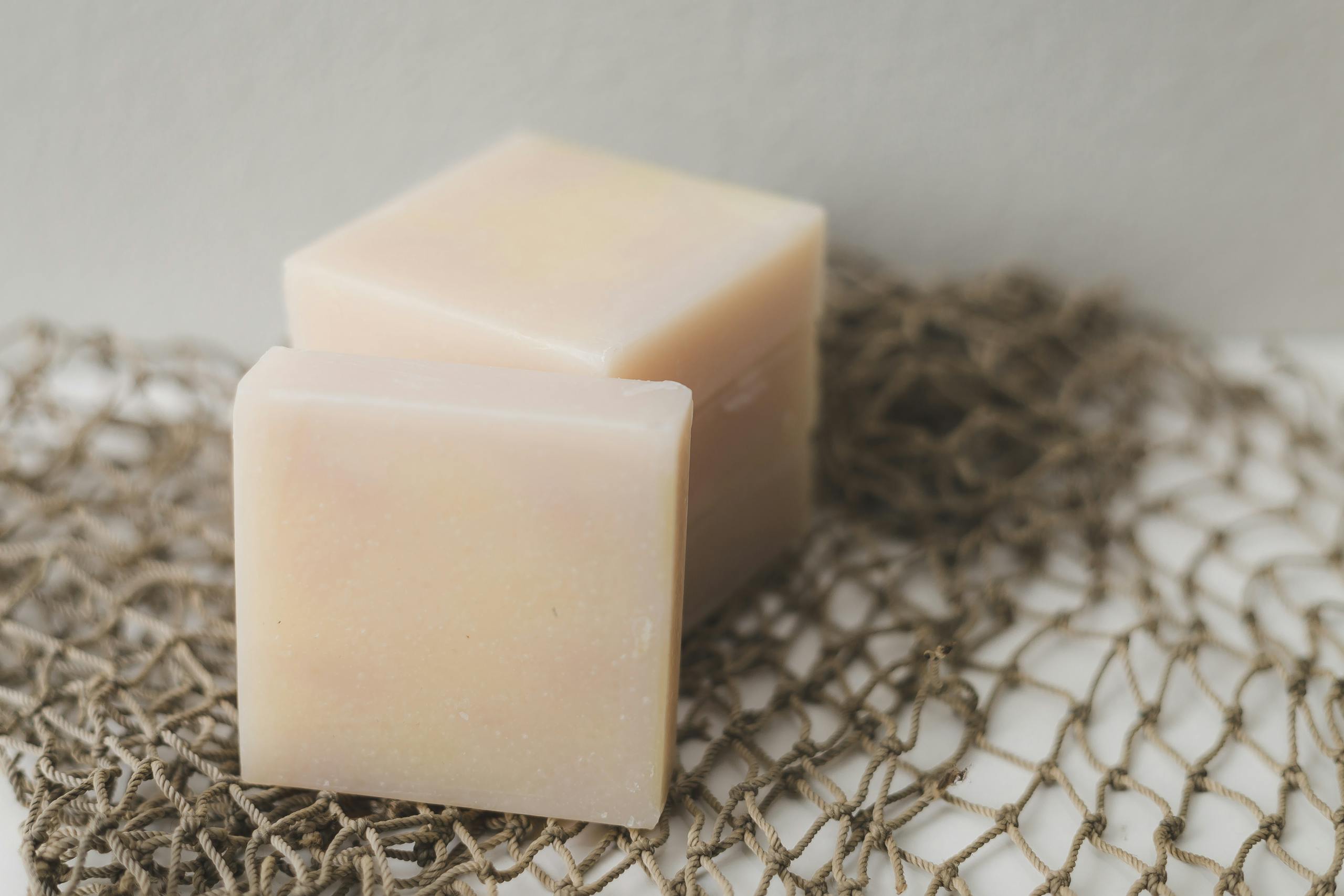 Two bars of natural handmade soap placed on a rustic netting backdrop, perfect for a spa theme.