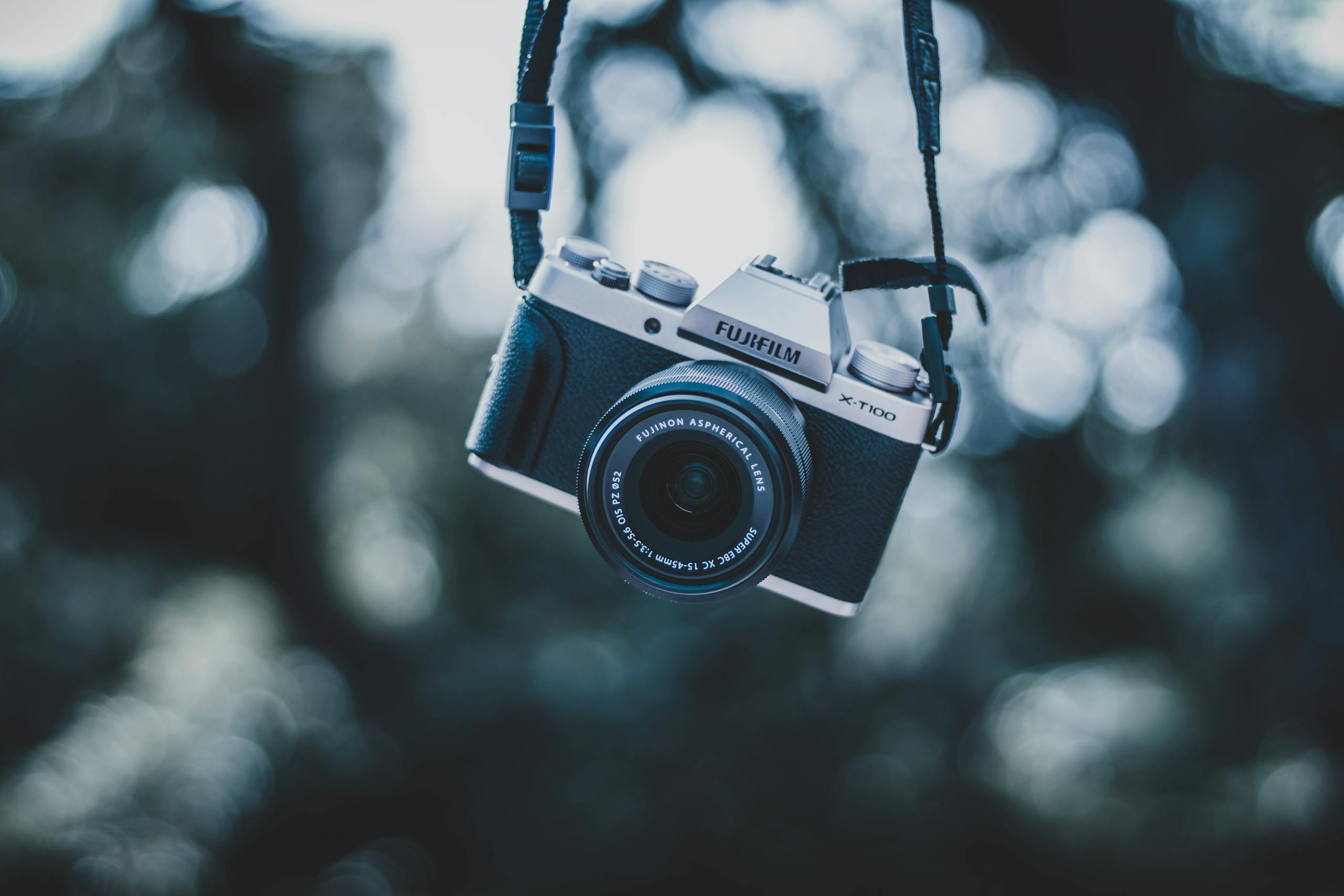 A vintage camera elegantly suspended, capturing a soft, dreamy bokeh background in an outdoor setting.