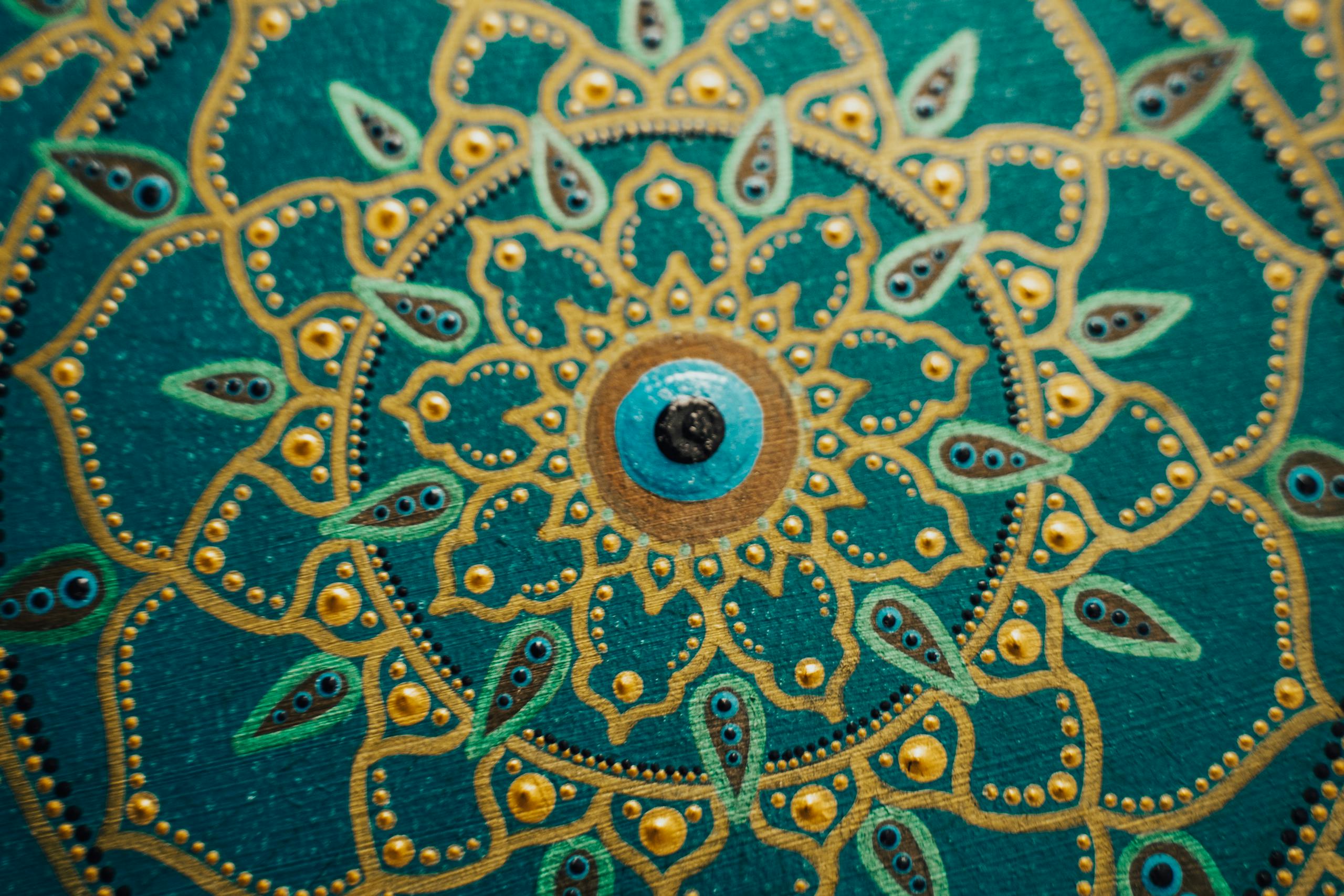 Detailed mandala artwork featuring gold and teal patterns, showcasing symmetry and creativity.