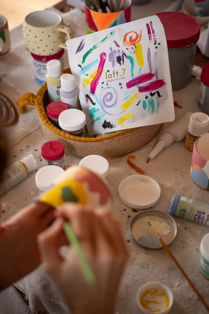 Colorful art supplies and a person painting in a creative workshop setting.